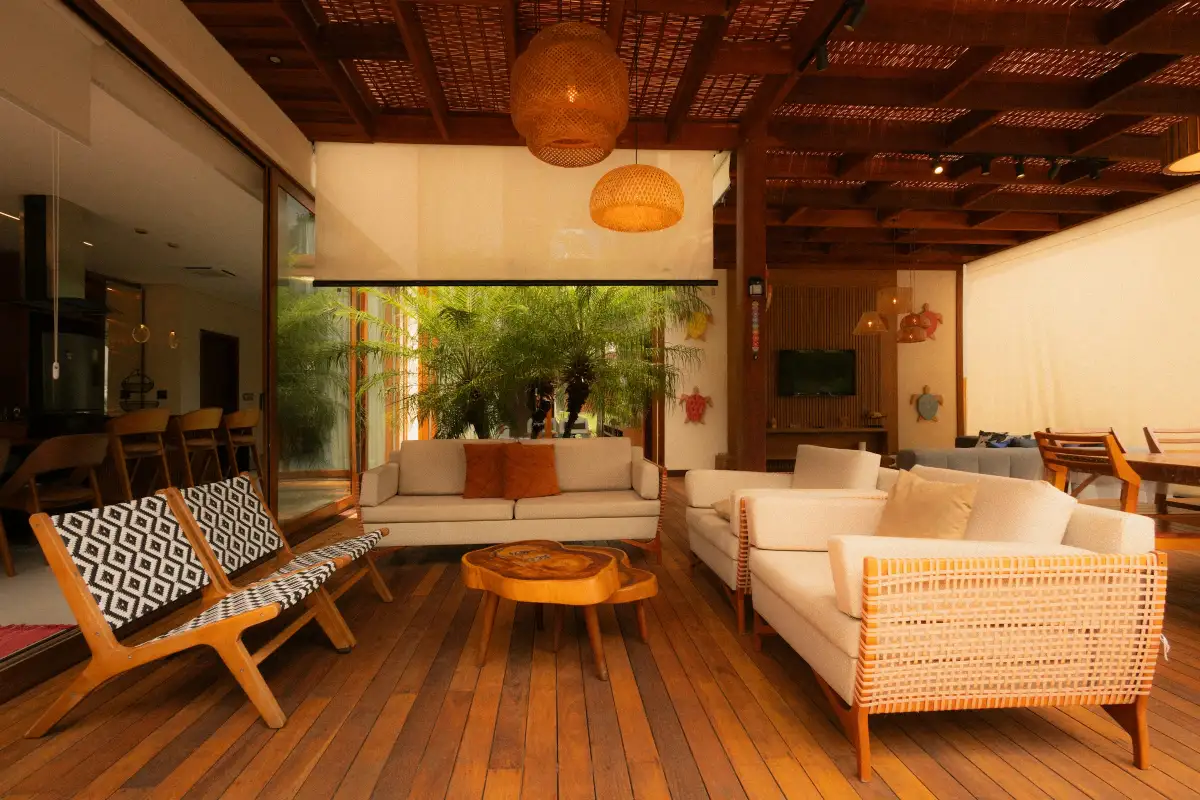 Phòng khách rộng có cửa kính trượt mở ra sân thượng, sofa chữ L và thảm sáng màu
