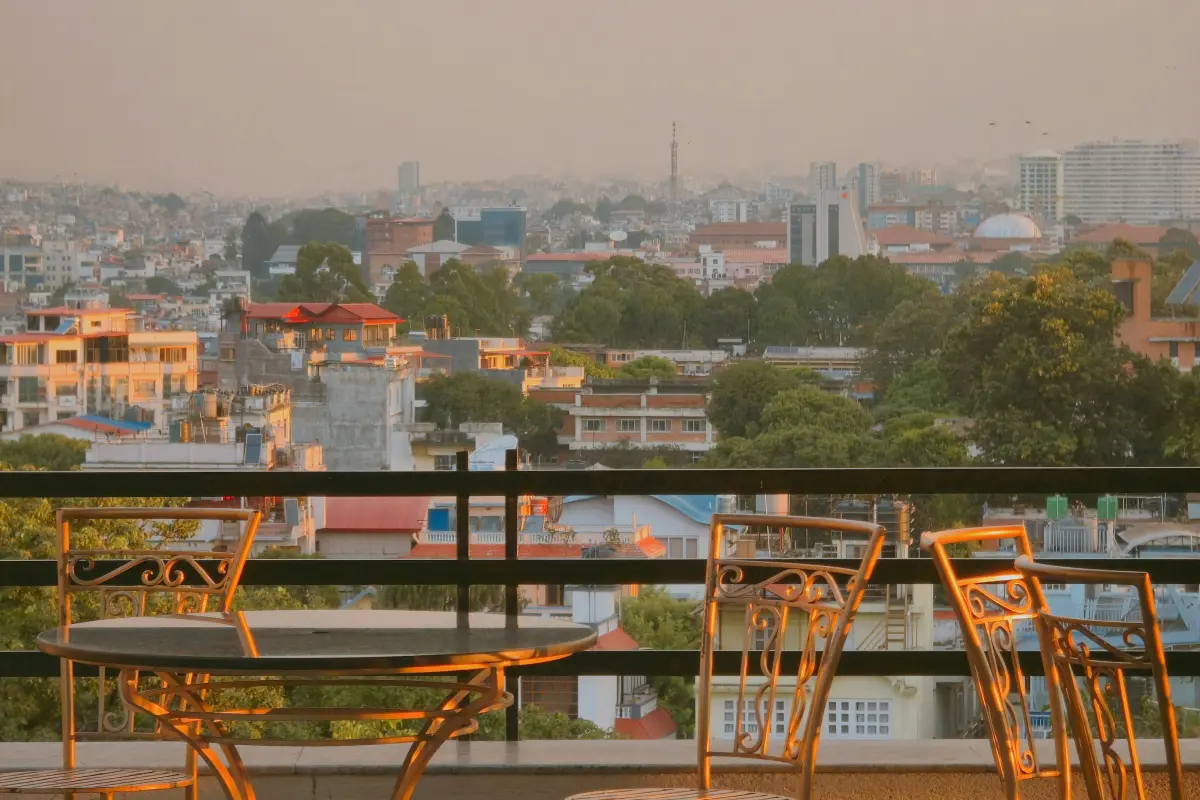 Sân thượng riêng lát gỗ với bàn ăn ngoài trời sáu ghế và dây đèn, trời chạng vạng