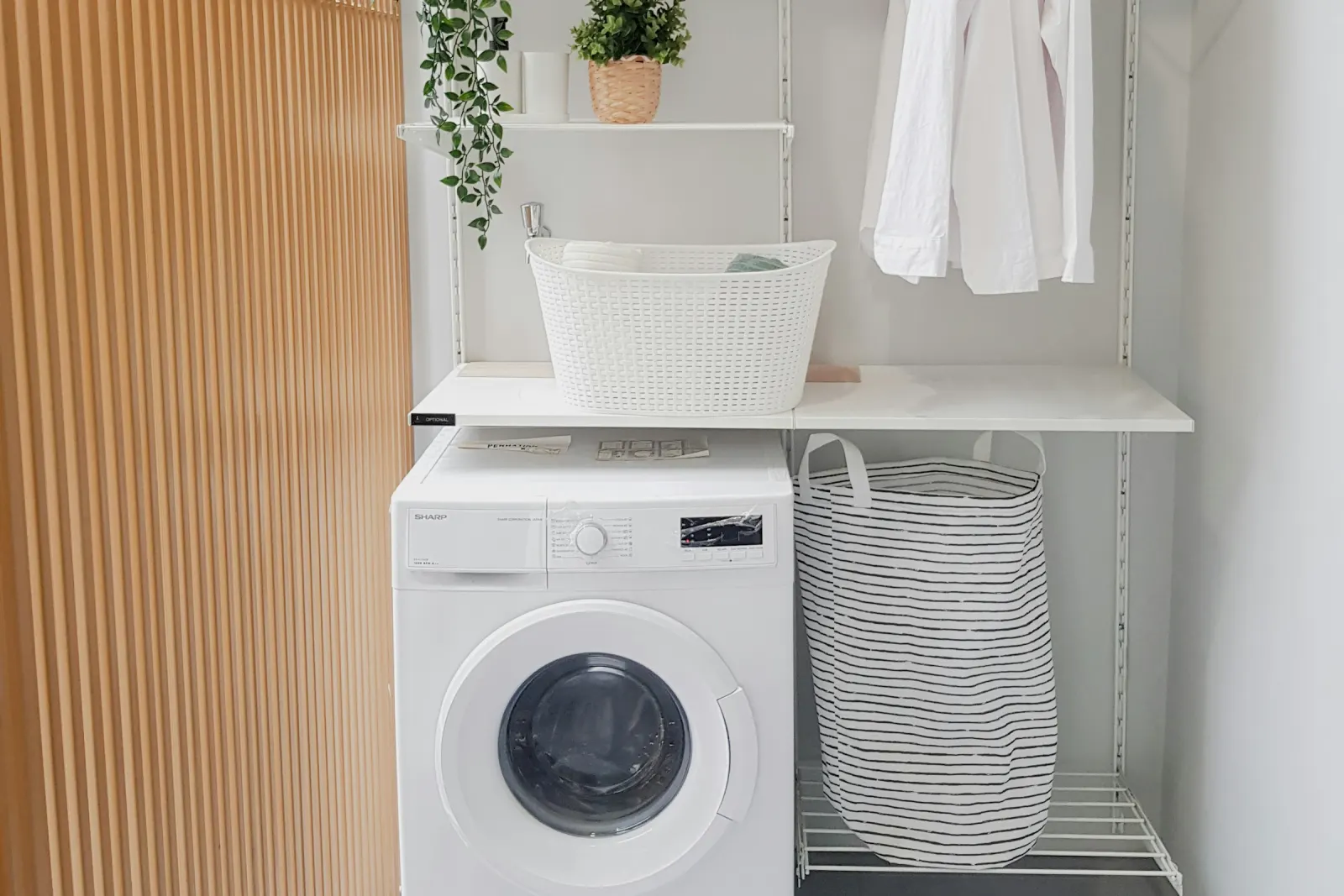 Góc giặt trong căn với máy giặt cửa trước, kệ để đồ và giá phơi gấp gọn