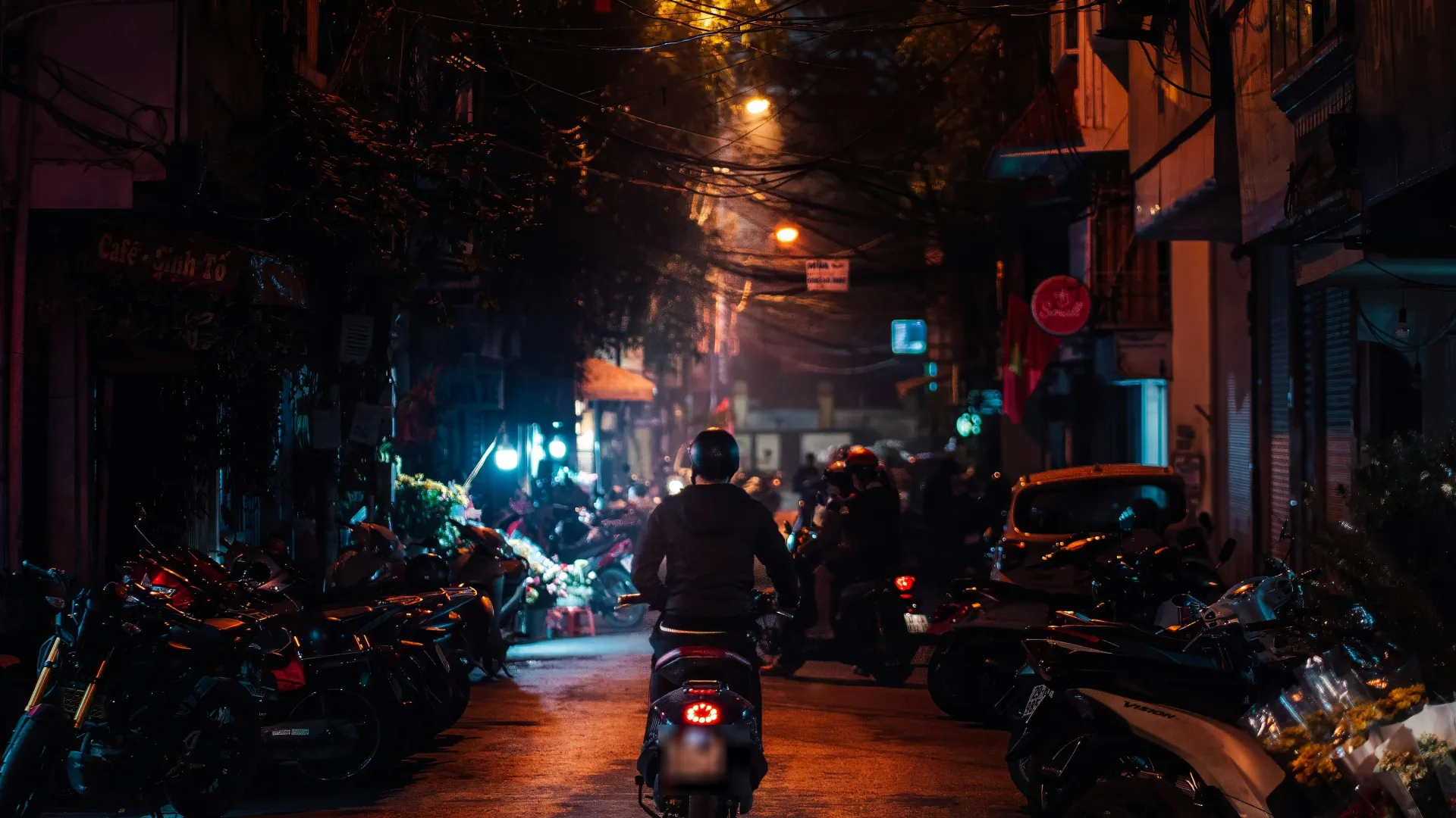 Một con phố nhỏ trong Phố Cổ Hà Nội buổi tối, đèn đường vàng, xe máy đỗ kín hai bên